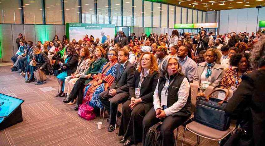 Personas sentadas en sillas a la espera de que hablen en el escenario.