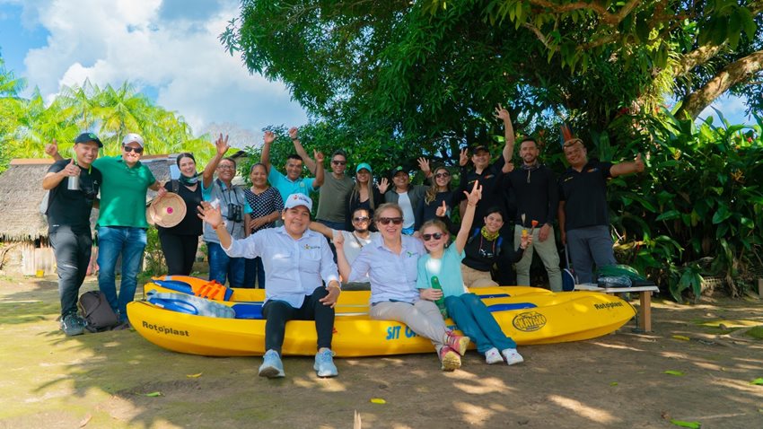 Personas posando para la foto, sentados en flotador grande amarillo al lado del río.