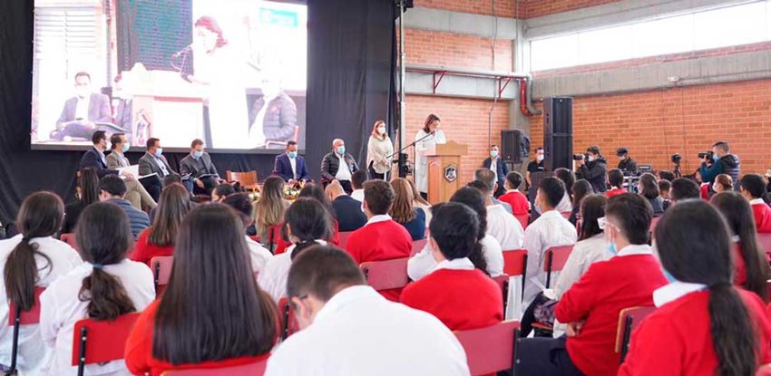 Ministra Ximena Lombana, junto a funcionarios del Gobierno, hablando desde un atril a estudiantes.