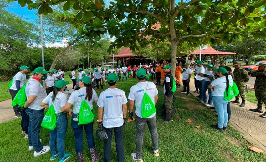 Personas reunidas en círculo, en un parque, con uniformes de Colombia Limpia listos para recolectar basuras.