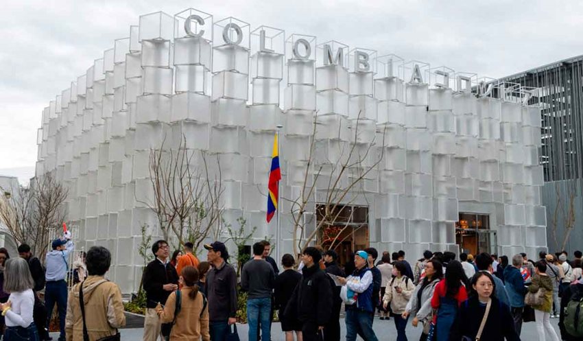 Personas caminando frente al pabellón de Colombia en Japón, que es blanco y con bandera del país a la entrada.