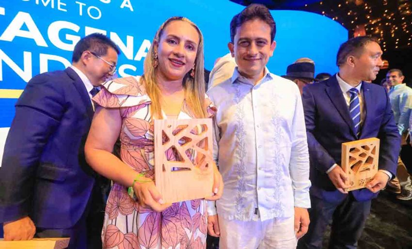 Mujer y hombre posando para la foto, mientras ella sostiene un premio en las manos.
