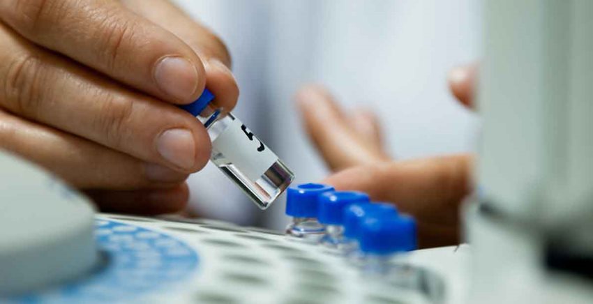 Mano agarrando tarritos de muestras médicas.