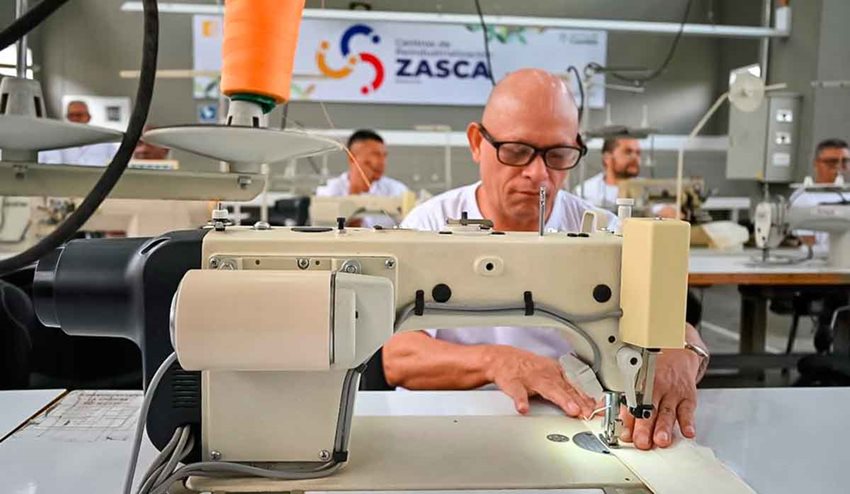 Hombre cosiendo una tela blanca en máquina.