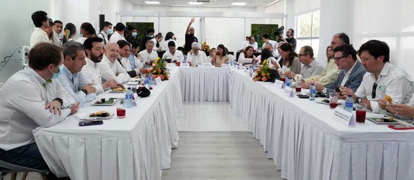 Funcionarios de los gobiernos de Colombia y Alemania, vestidos de blanco, sentados en una mesa dialogando.