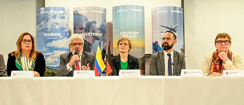 Dos hombres y tres mujeres sentados en mesa hablando a periodistas.