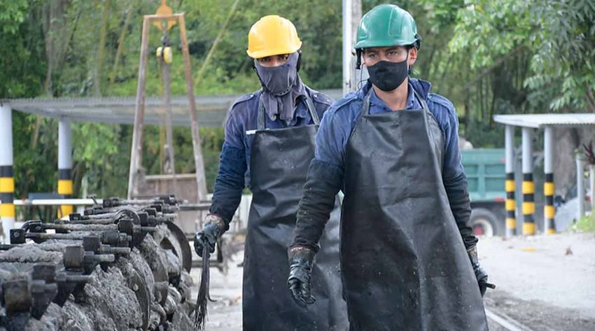 Dos hombres, con equipo de seguridad en terreno, caminando en medio de un espacio abierto de una mina.