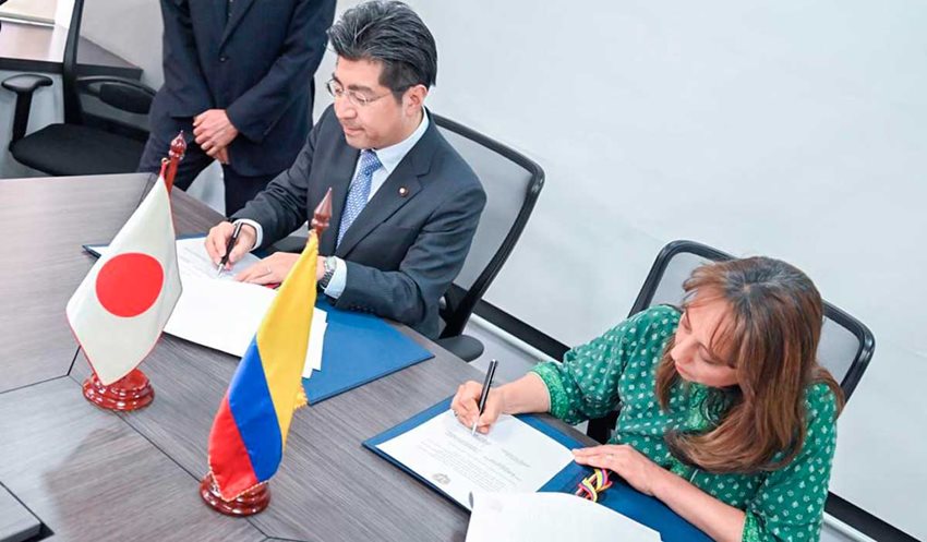 Viceministra Soraya Caro, junto a funcionario japonés, firmando documentos encima de una mesa.