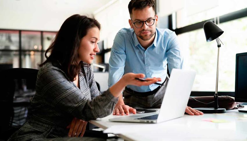 Mujer y hombre hablando frente a un computador portátil.