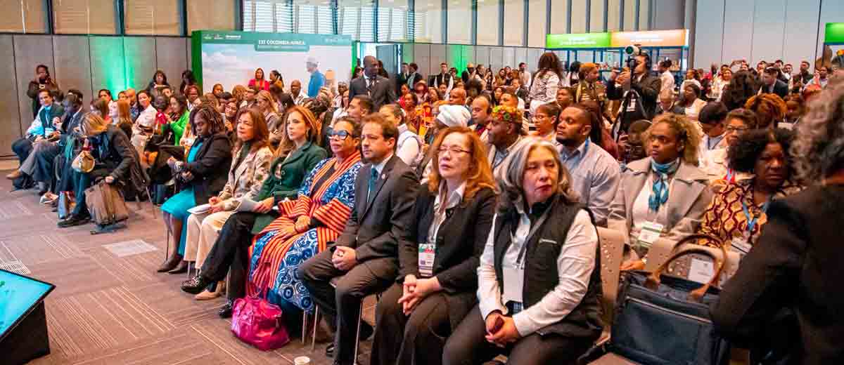 Descripción imagen: Personas sentadas en sillas a la espera de que hablen en el escenario.