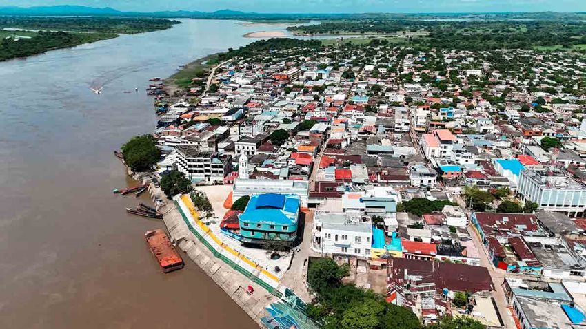 Foto panorámica, de día, de casas y edificios a la orilla de un río.