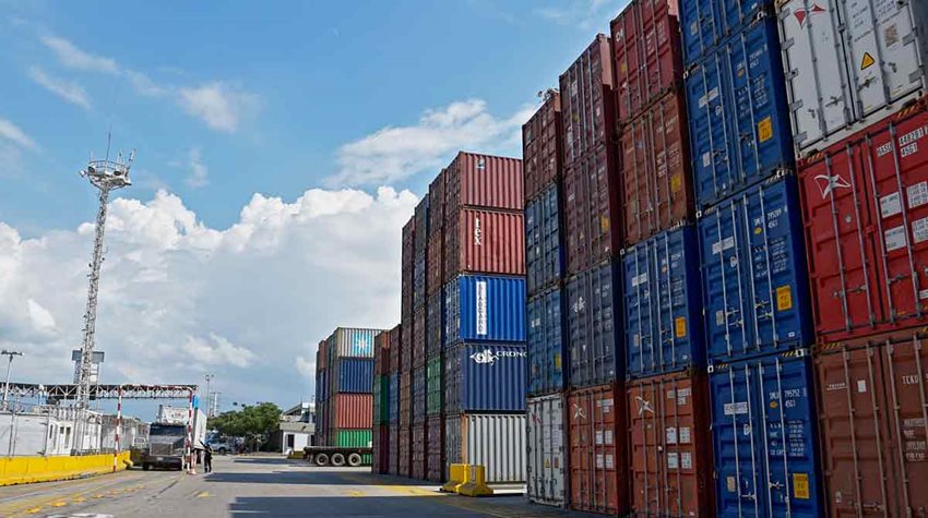 Contenedores de colores descargados y apilados en medio de calle de zona franca.