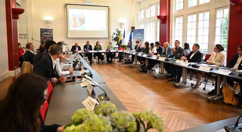 Personas reunidas alrededor de una mesa en U, dialogando.