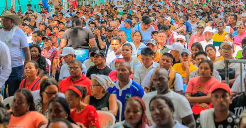 Muchas personas sentadas en sillas de un auditorio, prestando atención al escenario.