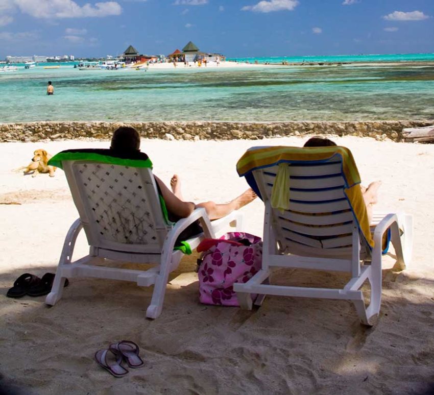 Personas sentadas en sillas de playa viendo el mar.