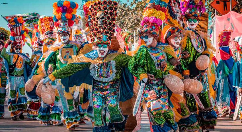 Personas con trajes y sombreros de colores y brillantes, festejando en medio del Carnaval de Barranquilla.