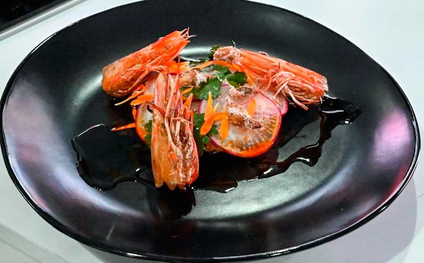 Plato plano, negro, con comida de mar dentro.