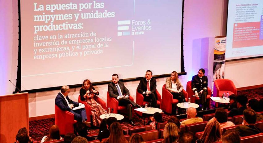 Mujeres y hombres sentados en sillas, en el escenario, hablándole al público en medio de un conversatorio.