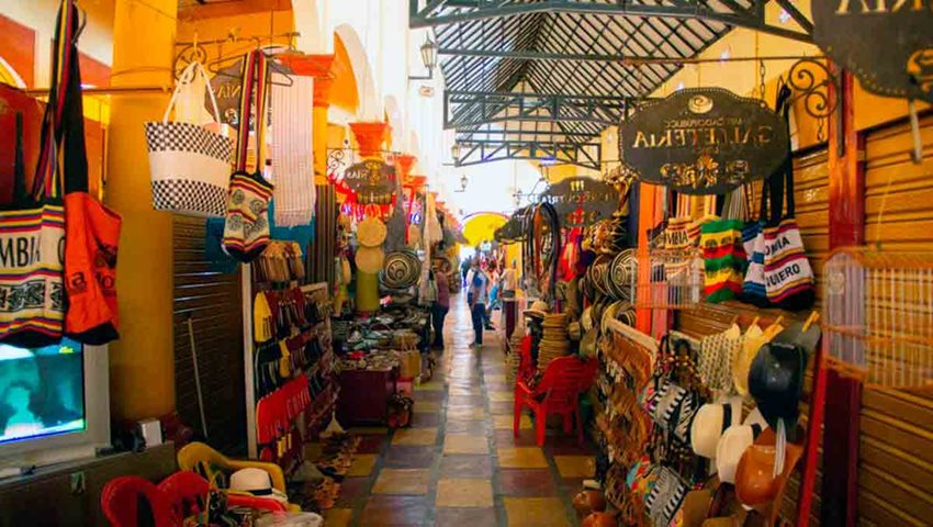 Fotografía de pasillo rodeado de tiendas de artesanías colombianas.