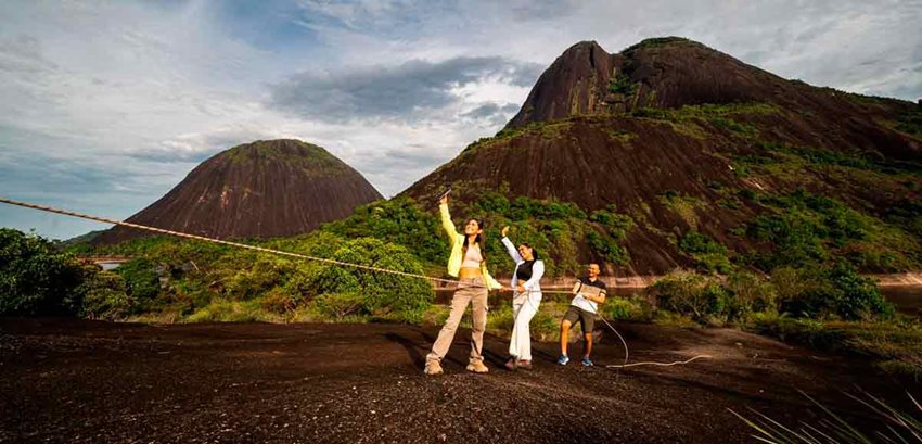 Dos mujeres y un hombre tomándose una selfie con los Cerros de Mavecure de fondo.