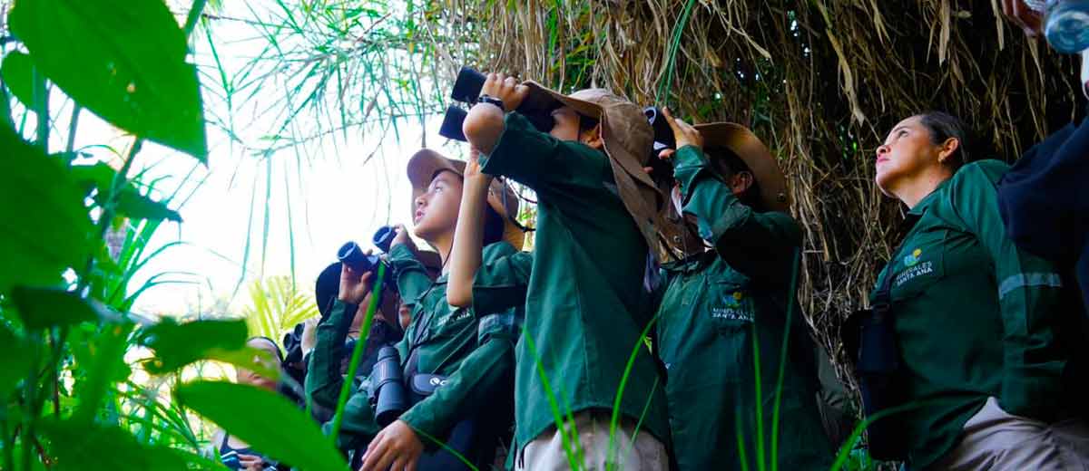 Descripción imagen: Turistas viendo aves, con binoculares, en selva colombiana.