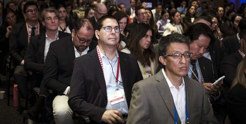 Personas sentadas en sillas dentro de auditorio.