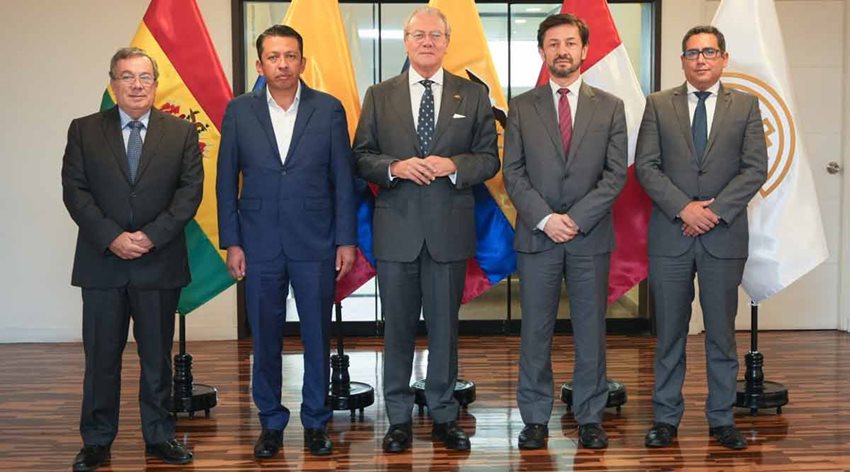 Cinco hombres, de traje, posando para la foto delante de banderas de países.