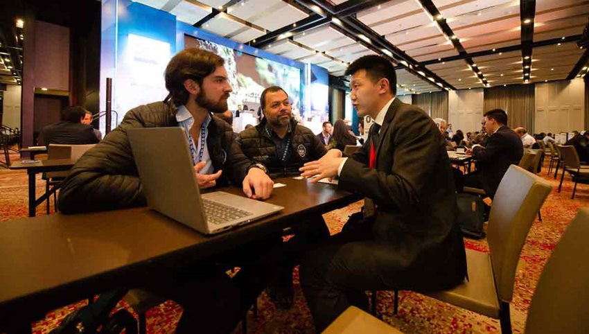 Tres hombres reunidos alrededor de una mesa, dialogando y negociando.