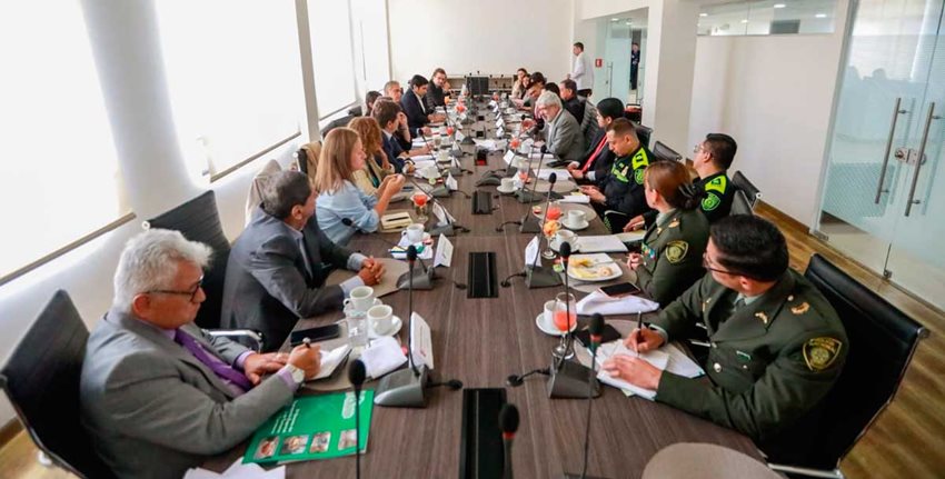 Ministro Umaña con personas del Gobierno, gremios y la Policía sentados en una mesa dialogando.