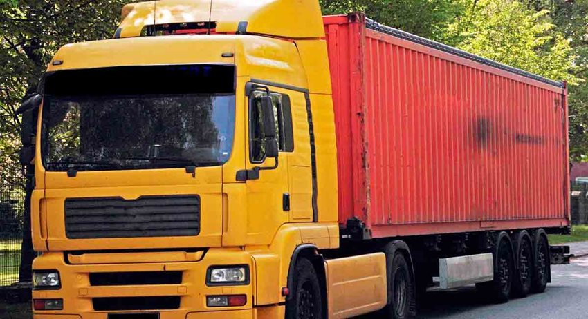 Camión amarillo con caja de carga rojo, estacionado en medio de la calle.