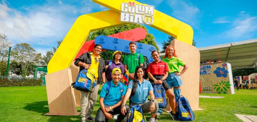 Siete jóvenes posando para la cámara, vistiendo camisas de colores vivos.