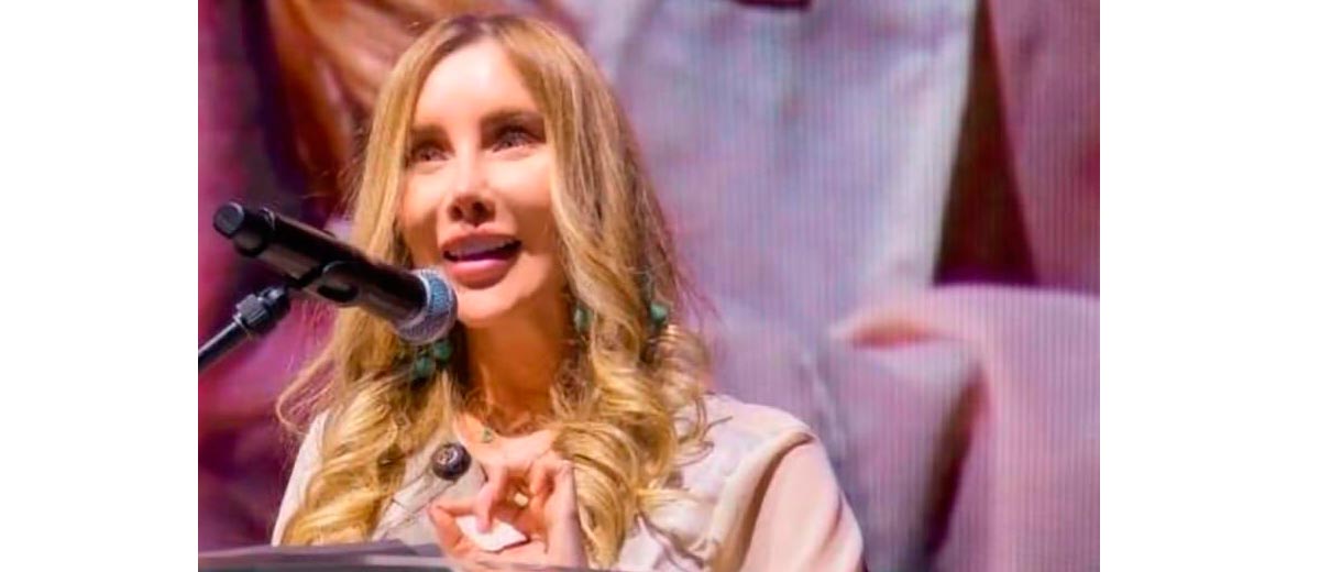 Descripción imagen: Ministra Diana Morales hablando por micrófono, en atril, desde el escenario.