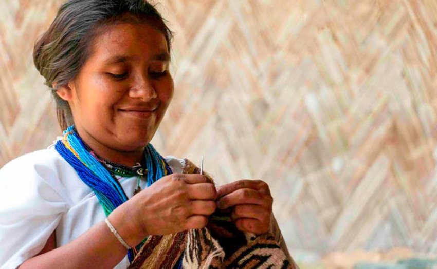 Una mujer artesana indígena tejiendo una mochila.