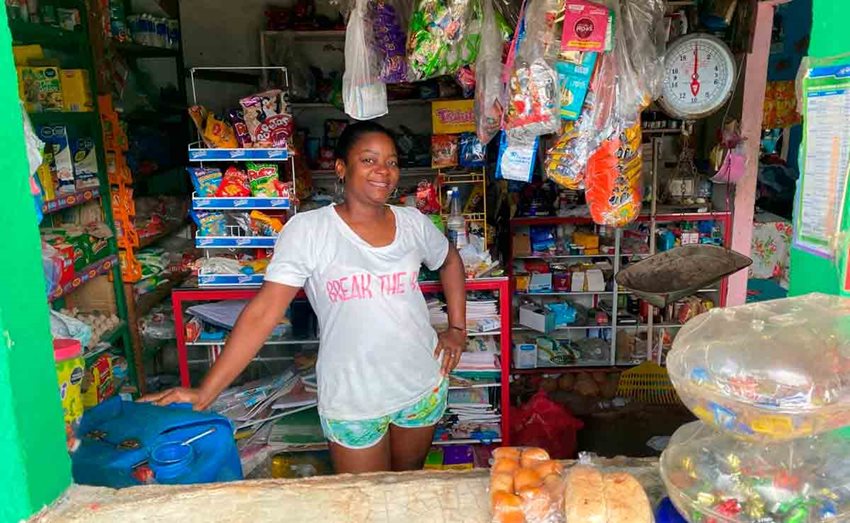 Mujer morena posando para la foto en medio de la mercancía de su tienda.
