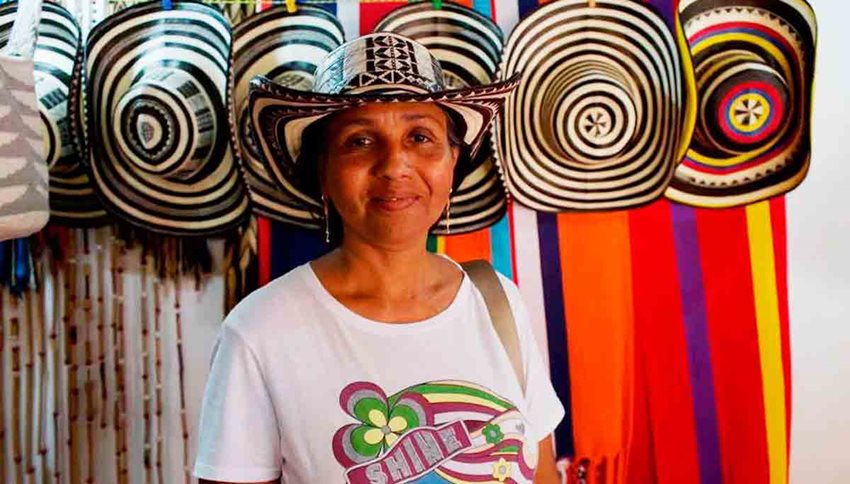 Mujer morena posando para la foto con un sombrero vueltiao puesto.