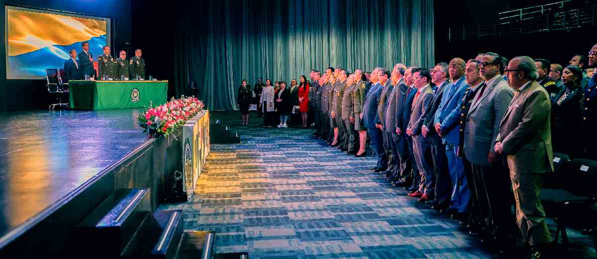 Descripción imagen: Altos directivos de pie en auditorio, en medio del evento de seguridad turística.