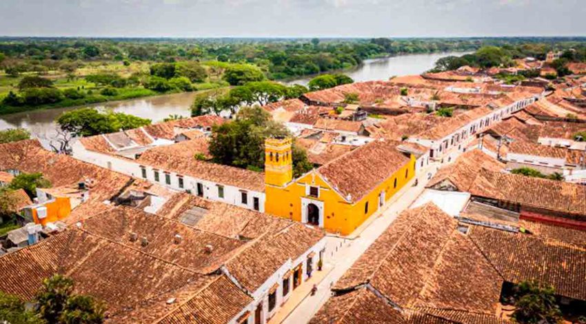 Panorámica de un pueblo a la orilla del mar y su iglesia amarilla.
