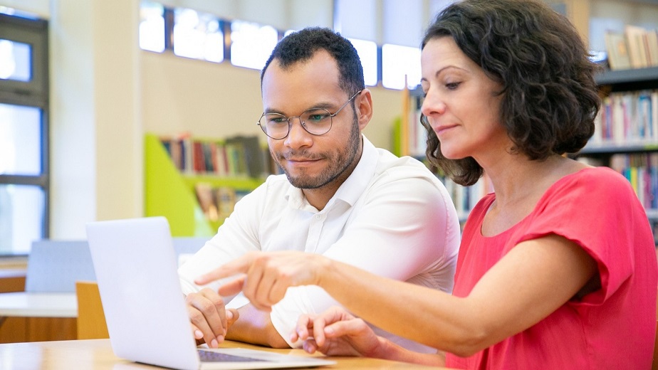 Descripción imagen: Hombre y mujer frente a computador portátil, revisando archivos.