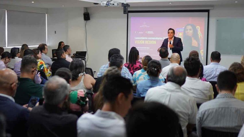 Hombre con micrófono en mano, hablándole al público asistente.