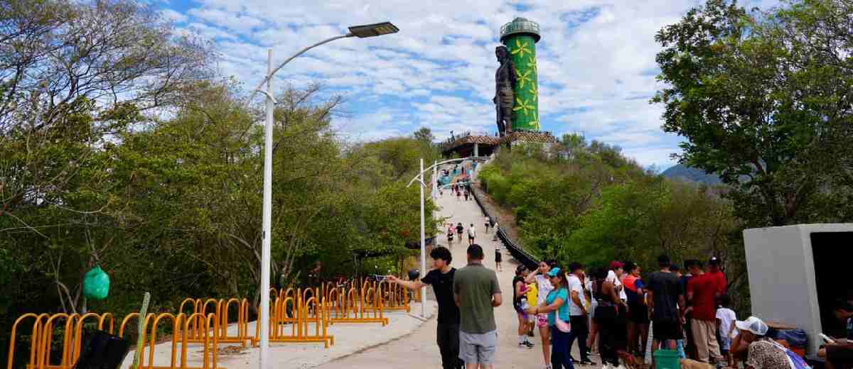 Descripción imagen: Fotografía de paisaje, en medio del parque, y personas caminando alrededor.