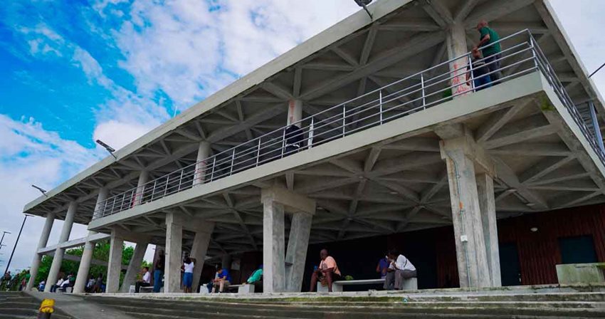 Fachada de construcción con personas sentadas alrededor.