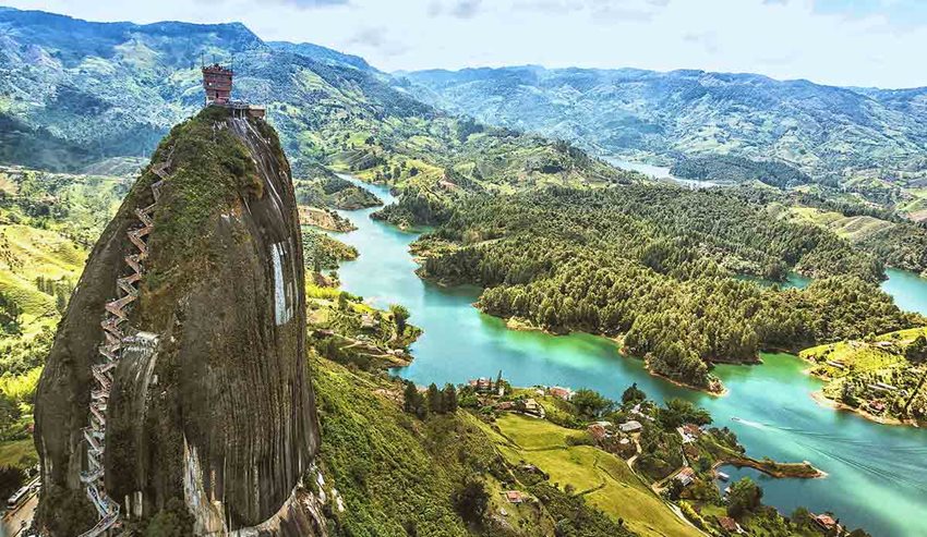 Panorámica de Guatapé, que consta de un paisaje con montañas y lago, y al lado una piedra gigante con escalera