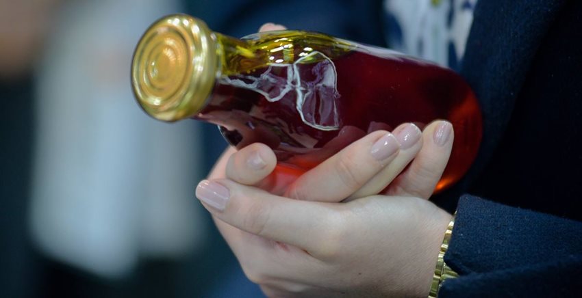 Manos sosteniendo una botella de vidrio llena con aceite de palma.