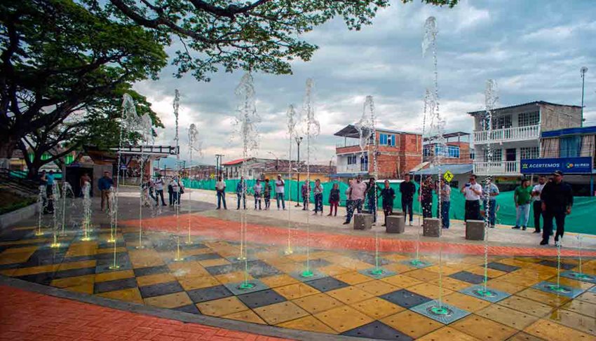 Personas en medio del parque, de día, viendo chorros de agua.