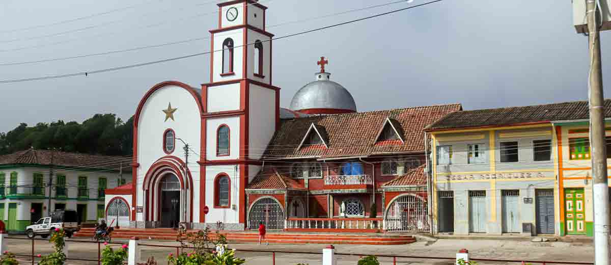 Descripción imagen: Foto, de día, de la iglesia de Murillo, en Tolima, con casas y el parque alrededor.