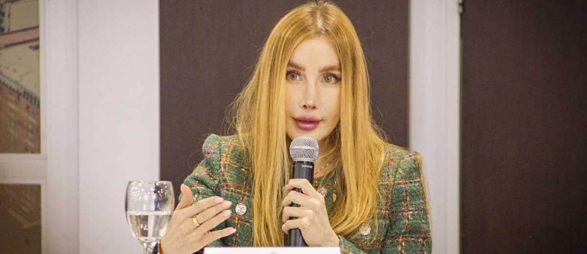 Descripción imagen: Ministra Diana Morales hablando por micrófono desde una mesa en donde está sentada.