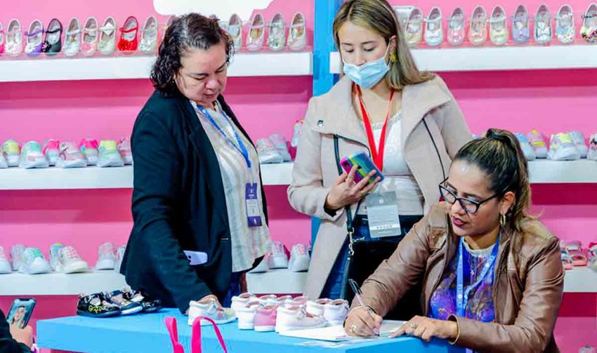 Tres mujeres reunidas en su stand de zapatos para niñas.