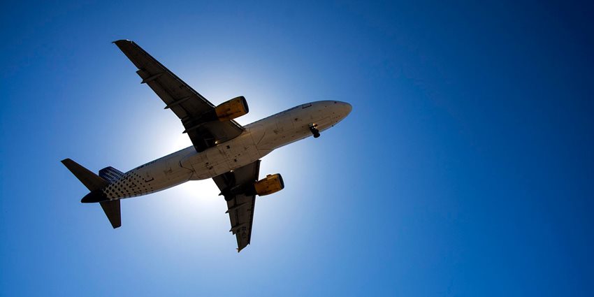 Fotografía de la parte de abajo de un avión, mientras vuela.