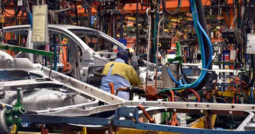 Personas, con elementos de seguridad, trabajando en taller de armado de autos.