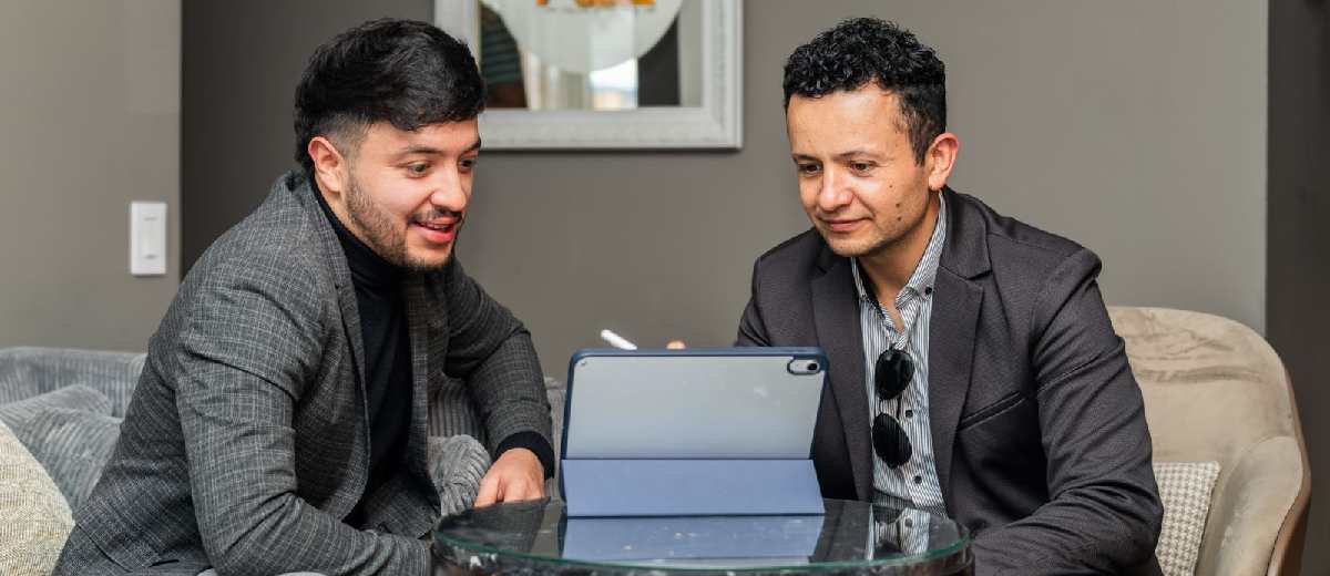 Descripción imagen: Dos hombres, de traje, frente a computador portátil revisando Circular Única de Calidad Turística.